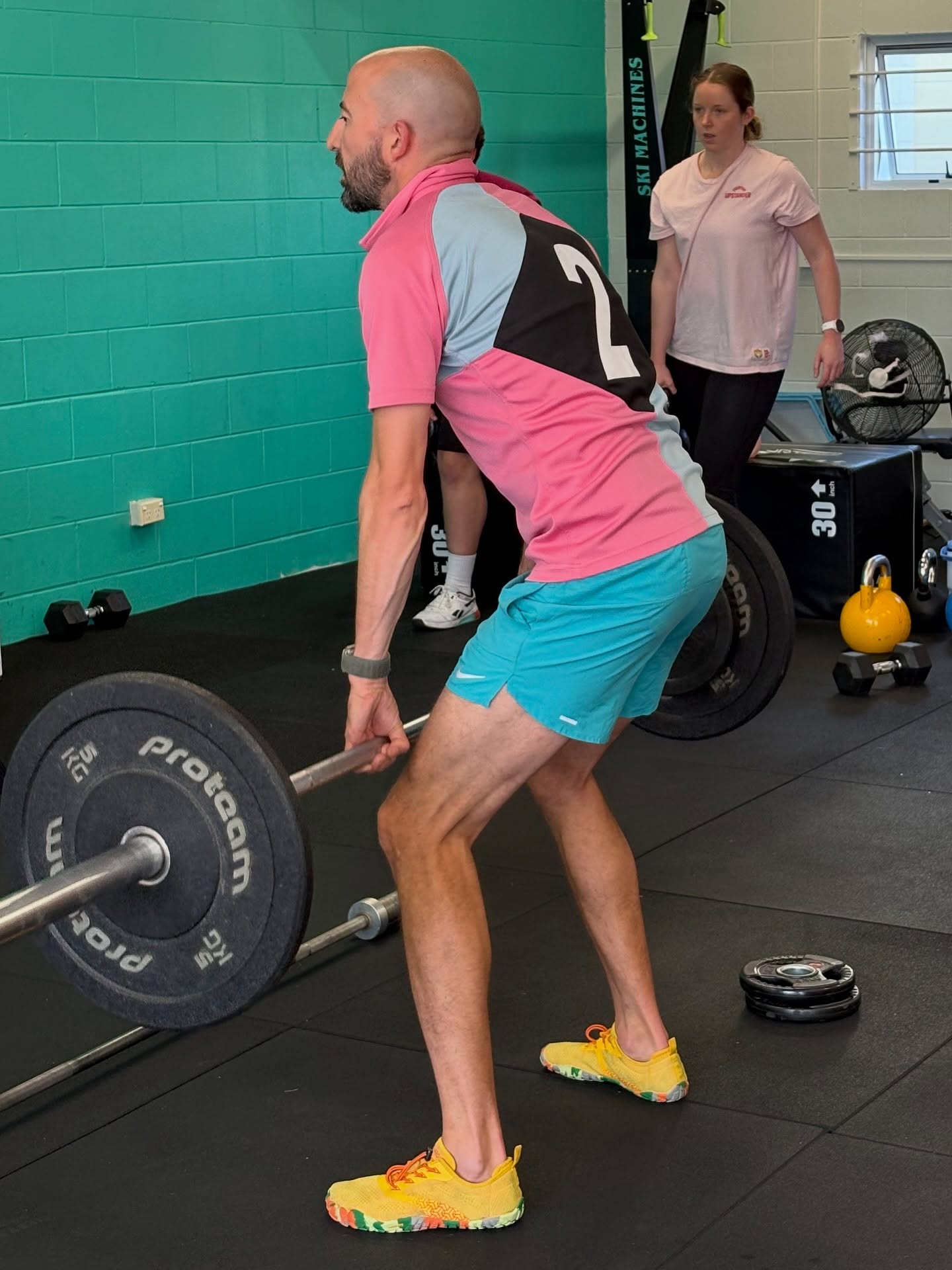 A member setting up a deadlift in class while a coach watches on
