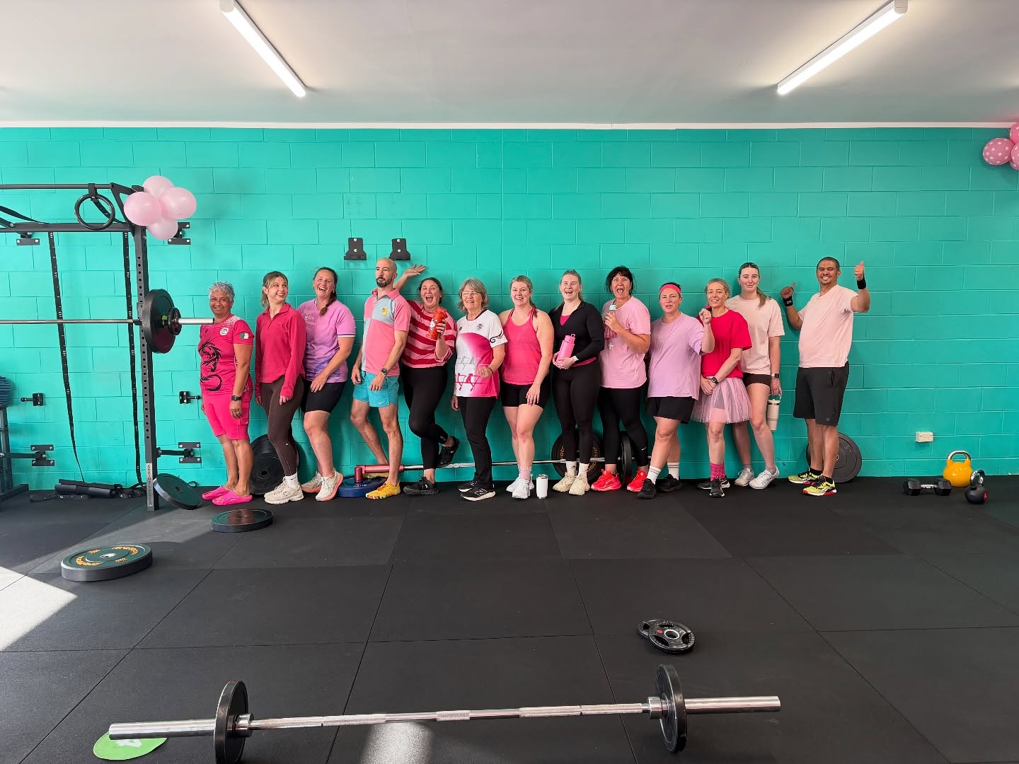 Club 31 members lined up along the teal wall after a class, smiling